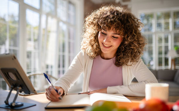 Woman journaling at a desk in a bright modern home, symbolizing self-reflection and personal growth.
